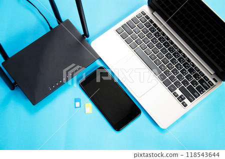 WiFi router, SIM card, smartphone, laptop computer placed on blue background. Communication equipment WiFi router, SIM card, smartphone, laptop computer placed on blue background. Communication equipment 118543644
