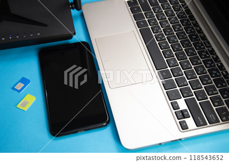 WiFi router, SIM card, smartphone, laptop computer placed on blue background. Communication equipment 118543652