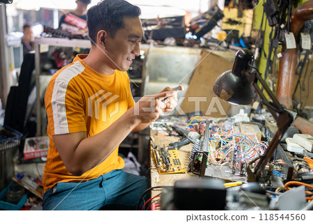 repair man takes a photo of a circuit using a cell phone repair man takes a photo of a circuit using a cell phone 118544560