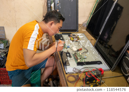 male technician uses soldering iron to repair electronic components male technician uses soldering iron to repair electronic components 118544576