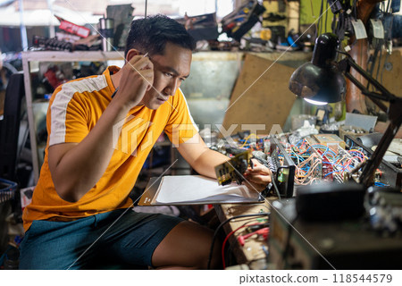 male technician observing the circuit while working at the workbench male technician observing the circuit while working at the workbench 118544579