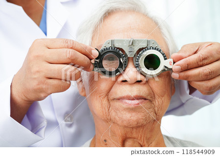 Optometrist checking Asian elderly woman ophthalmic vision eye test and using optical trial frame. 118544909