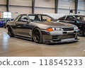A sleek silver car with shiny alloy wheels parked on a gray surface 118545233