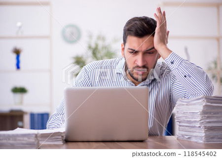 Young male employee and too much work in the office 118545402