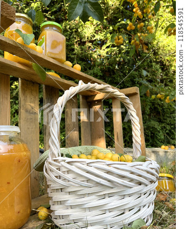 Rolled jars with jam under tree with apples. Harvest in garden. Small yellow apples for dessert, preparation for winter. Organic product. Rolled jars with jam under tree with apples. Harvest in garden. Small yellow apples for dessert, preparation for winter. Organic product. 118545591