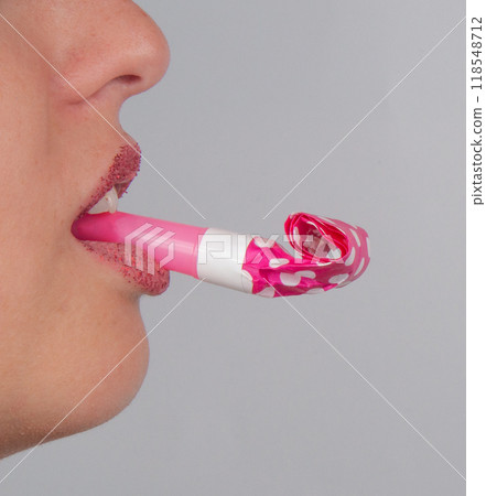 Foil whistle horn or pink noisemaker in mouth on the white Foil whistle horn or pink noisemaker in mouth on the white 118548712