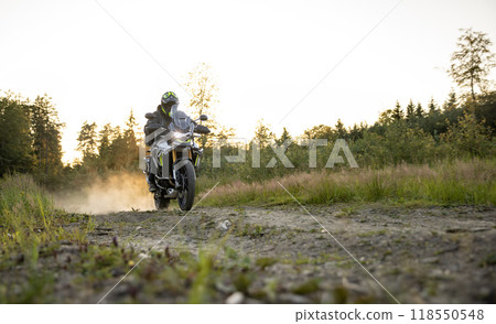 Driver riding motorcycle on empty road during sunset Driver riding motorcycle on empty road during sunset 118550548
