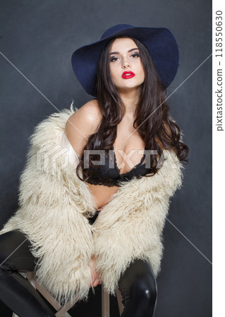 Cute fashion model woman in blue classic hat and white fur coat posing indoor 118550630