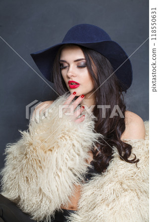 Pretty woman with red lips make-up and long wavy hair wearing blue hat  118550631