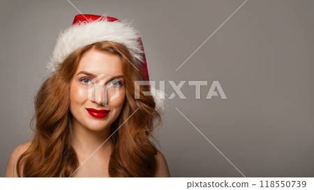 Pretty Christmas woman in Santa hat with make-up and cute positive smile looking at camera Pretty Christmas woman in Santa hat with make-up and cute positive smile looking at camera 118550739