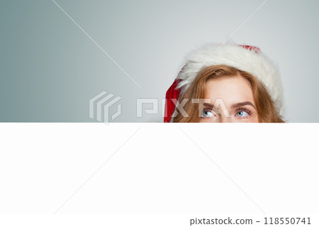 Christmas woman in Santa hat holding white empty banner board Christmas woman in Santa hat holding white empty banner board 118550741