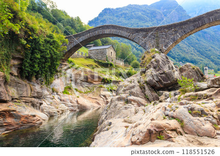 Ancient double arch stone Roman bridge (Ponte dei Salti) over the clear water of the Verzasca river in Lavertezzo ,Verzasca Valley, Ticino Canton, Switzerland 118551526