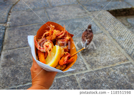 Typical Italian appetizer (Fritto misto di pesce) mix of fried seafood i female hand. Healthy snack in Genoa, Cinque Terre and Portofino 118551598