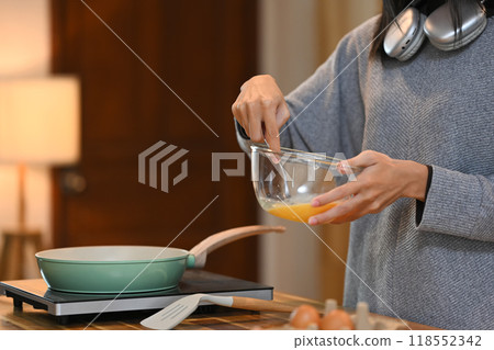 Cropped shot of young woman beating eggs in a bow with fork, making breakfast in the kitchen Cropped shot of young woman beating eggs in a bow with fork, making breakfast in the kitchen 118552342