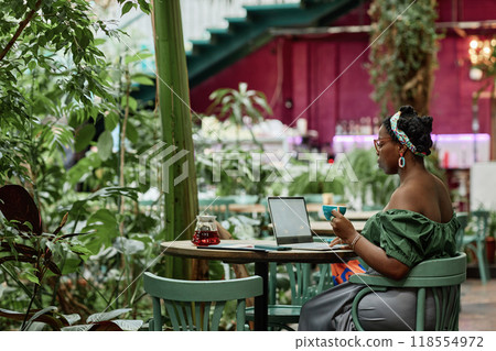 African American female freelancer working remotely in eco cafe, she drinking black tea African American female freelancer working remotely in eco cafe, she drinking black tea 118554972