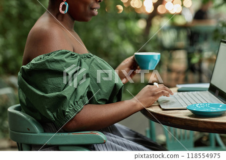Side view shot of unrecognizable woman typing on keyboard while holding coffee cup Side view shot of unrecognizable woman typing on keyboard while holding coffee cup 118554975