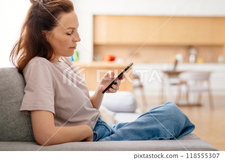 Young woman using her smartphone at home. 118555307