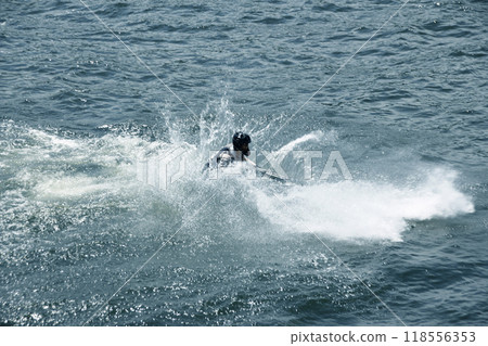 The jet ski jumps and lands, sending up waves. 118556353