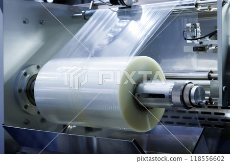 roll of plastic packaging film on the automatic packing machine in food product factory. industrial and technology concept. 118556602