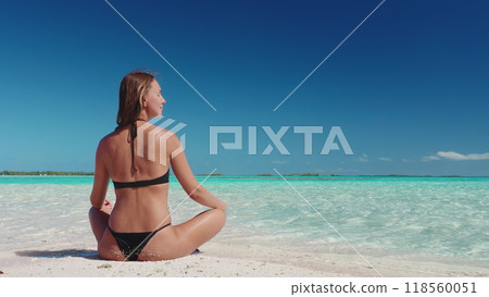 Beautiful woman relax on Bora Bora tropic sand beach. Crystal turquoise water, white sand, blue sky, sunny day. Caucasian female in bikini sit enjoy outdoor lifestyle travel on summer holiday vacation 118560051