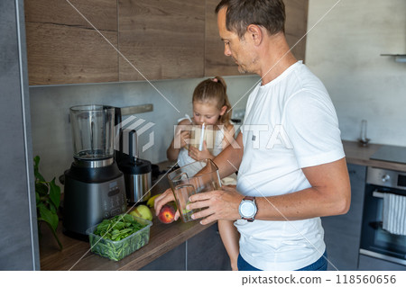 Family with a young father and his little daughter preparing fruit for a healthy juice or smoothie in home kitchen Family with a young father and his little daughter preparing fruit for a healthy juice or smoothie in home kitchen 118560656