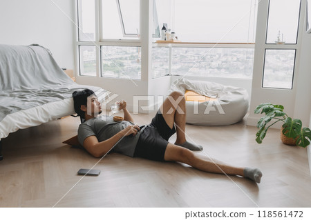 Man lying on the floor of the living room watching movie on weekend. 118561472
