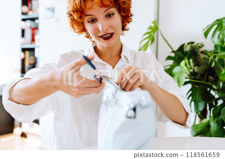 young red-haired attractive woman unpacking parcel at home 118561659