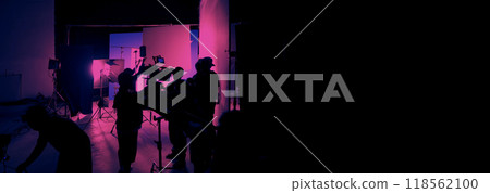 Silhouette of film crews and video camera on special dolly crane with film lights equipment and blue screen set. Film Production behind the scenes studio set in silhouette style. Behind video shooting 118562100