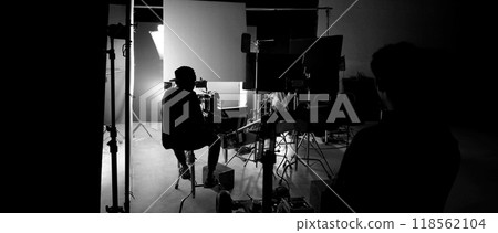 Silhouette of film crews and video camera on special dolly crane with film lights equipment and blue screen set. Film Production behind the scenes studio set in silhouette style. Behind video shooting 118562104