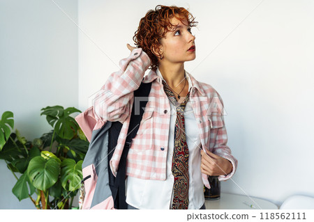 attractive extravagantly dressed young woman, student, schoolgirl with red curly hair with backpack in home interior attractive extravagantly dressed young woman, student, schoolgirl with red curly hair with backpack in home interior 118562111