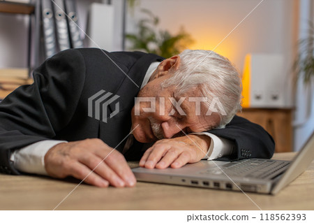 Bored sleepy senior businessman working on laptop leaning on hand falling asleep at office desk 118562393
