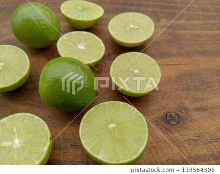 Several Mexican limes (whole and half cut) on a wooden table. From Mexico 118564306
