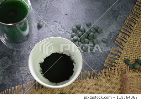 A bowl of green seaweed powder, pills and capsules. A bowl of green seaweed powder, pills and capsules. 118564362