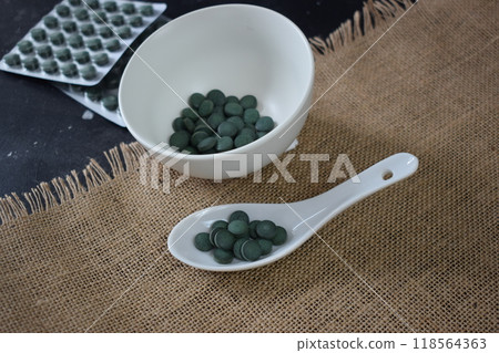 Green seaweed powder, pills and capsules in a bowl 118564363