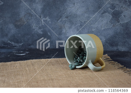 Green seaweed powder, pills and capsules in a cup on a black background 118564369