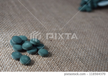 Green seaweed powder, pills and capsules on a fabric background 118564370