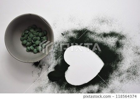 A bowl of green seaweed powder, pills and capsules 118564374