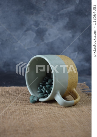 Green seaweed powder, pills and capsules in a cup on a black background 118564382