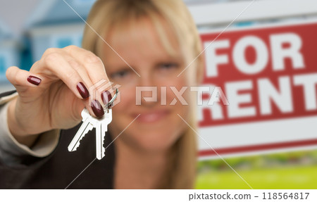 Female Real Estate Agent Presenting House Keys In Front of For Rent Sign & House. Focus is on the Keys. Female Real Estate Agent Presenting House Keys In Front of For Rent Sign & House. Focus is on the Keys. 118564817