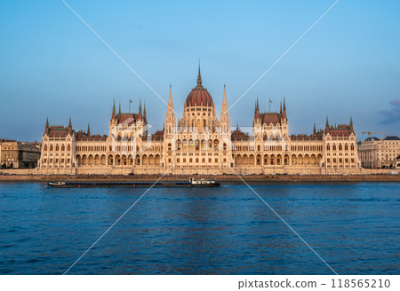 Budapest, Hungary. August 25, 2022. Amazing sunset shot of the parliament. The warm light of the golden hour enhances the beauty and elegance of the building. Budapest, Hungary. August 25, 2022. Amazing sunset shot of the parliament. The warm light of the golden hour enhances the beauty and elegance of the building. 118565210