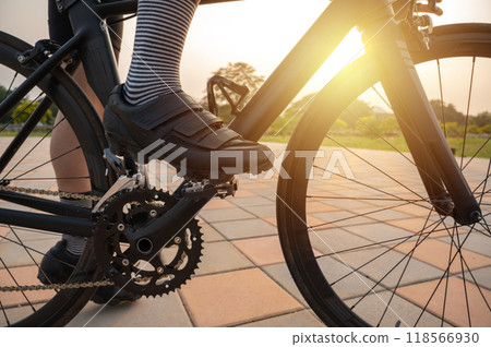 Cropped shot of female cyclist seated on her bicycle, ready for exercise during the sunset. Bike riding is an excellent cardio workout. It can help boost your heart and lung health. Cropped shot of female cyclist seated on her bicycle, ready for exercise during the sunset. Bike riding is an excellent cardio workout. It can help boost your heart and lung health. 118566930