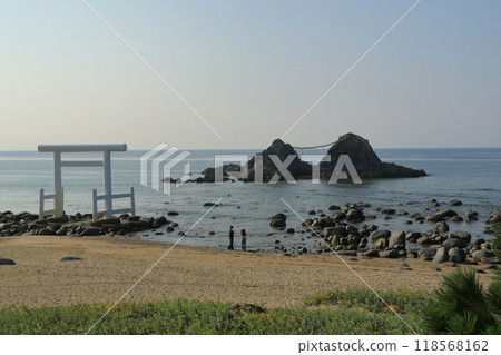 A couple looking at the Meoto Iwa rocks from the beach at Futamigaura in Sakurai, Itoshima A couple looking at the Meoto Iwa rocks from the beach at Futamigaura in Sakurai, Itoshima 118568162