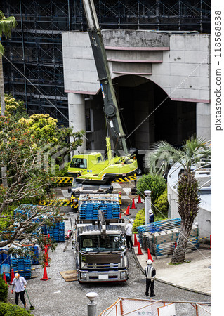 A crane lifting scaffolding and other temporary construction materials to a high altitude at a construction site for large-scale repair work on an apartment building A crane lifting scaffolding and other temporary construction materials to a high altitude at a construction site for large-scale repair work on an apartment building 118568838