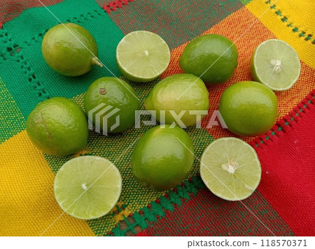 Mexican limes (7 whole and 2 halves) on a colorful tablecloth from Mexico Mexican limes (7 whole and 2 halves) on a colorful tablecloth from Mexico 118570371