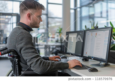 A man in wheelchair is focused on updating software at modern office 118570976