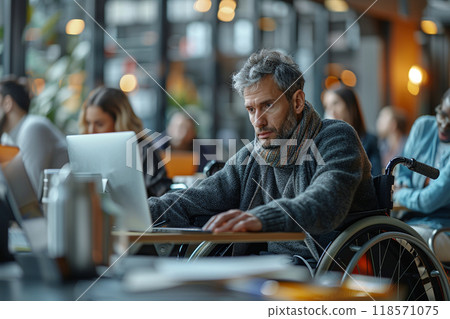 Inclusive office environment with man in wheelchair working intently 118571075