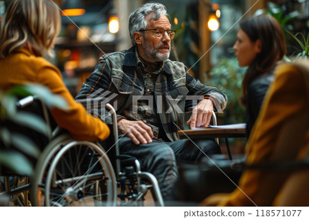 Inclusive office environment with man in wheelchair engaging in conversation 118571077