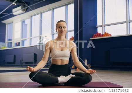 Woman meditating in a fitness studio during morning workout session 118571682