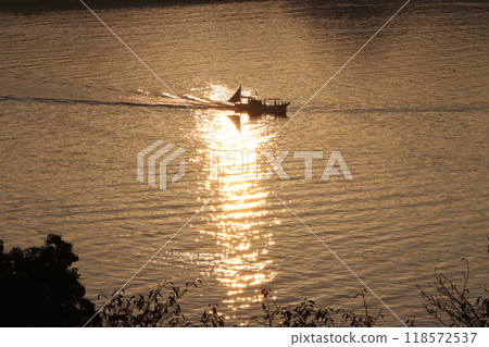 A fishing boat leaving in the morning sun A fishing boat leaving in the morning sun 118572537