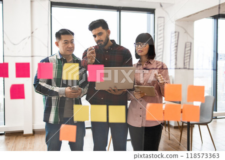 Diverse team brainstorming with sticky notes in modern office 118573363